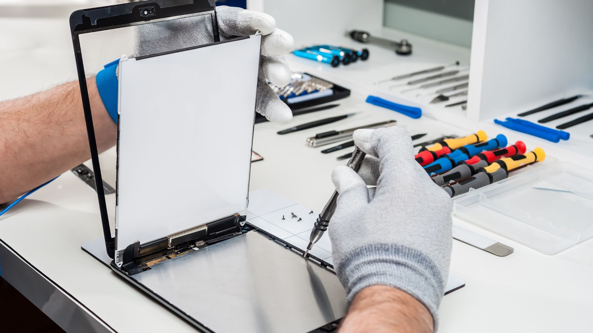 A man is working on a laptop with tools