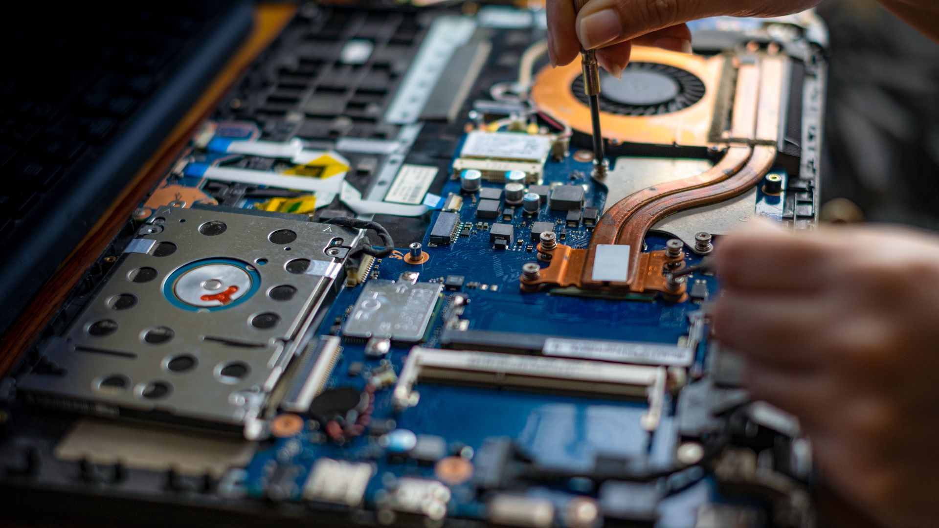 A person working on a motherboard of a laptop