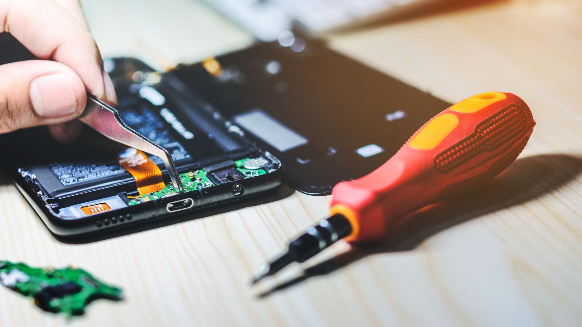 A person using a pair of scissors to cut a piece of circuit board